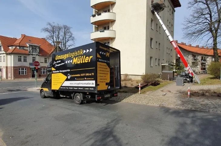 umzugswagen und moebellift vor mehrfamilienhaus